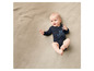 Bébé sur une couverture en tricot beige avec un body noir à imprimé animal.