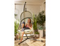Une femme se relaxant dans un fauteuil suspendu sur un balcon.