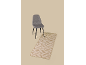 Chaise grise à pieds noirs et tapis beige à motif géométrique.