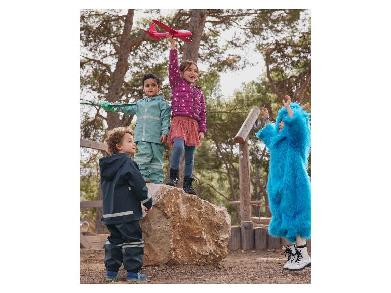 Des enfants jouent dehors avec des jouets et portent des vêtements colorés.