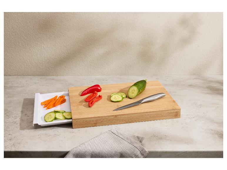 Planche à découper en bambou avec tiroir, légumes coupés et couteau sur un comptoir.