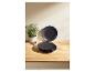 Assiettes noires empilées sur une table en bois avec une plante et un petit bol.