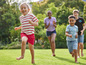 Des enfants courent pieds nus sur l'herbe.