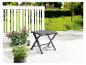 Un tabouret pliant gris sur une terrasse avec des plantes.