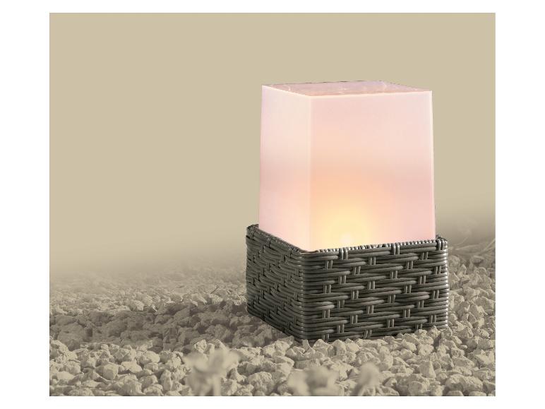 Lampe carrée avec base tressée grise et dessus blanc lumineux sur des galets.