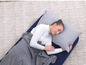 Une femme dort sur un matelas pneumatique avec une couverture et un oreiller.