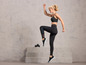 Une femme en vêtements de sport noirs de Jette Sports avec des chaussures de sport et des haltères.