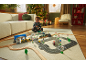 Enfant jouant avec un train en bois et un tapis de route sur un tapis dans un salon festif.