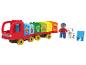 Un camion rouge avec des blocs de fruits et légumes, une figurine et un chien.