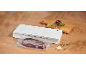 Machine sous vide avec viande emballée sous vide, planche à découper, oignon et herbes