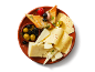 Assiette de fromages avec olives, pain grillé et tomates sur un plat de service marron.