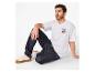 Homme en t-shirt blanc avec le numéro 23 et jean foncé, assis sur le sol.