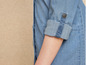 Gros plan d'une robe en jean avec un bouton sur la manche.