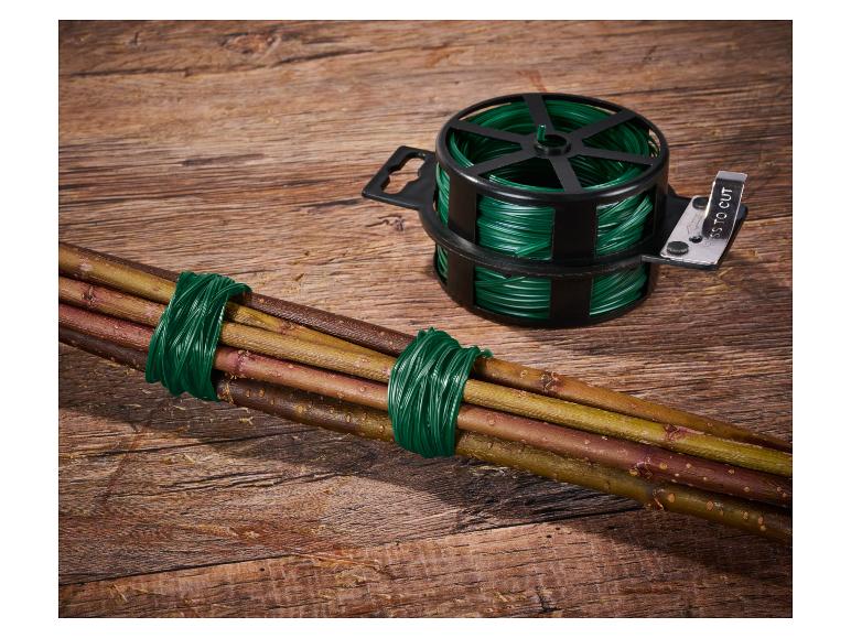 Fil de jardinage vert dans un distributeur avec coupe-fil et un paquet de branches attachées sur fond de bois.