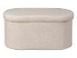 Pouf ovale moelleux, recouvert d'un tissu beige clair duveteux.