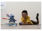 Un garçon joue avec une figurine Stitch sur un skateboard et une télécommande.