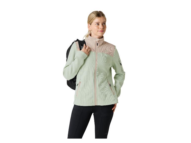 Femme en veste polaire vert clair et beige et legging noir, portant un sac à dos.