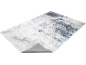 Tapis abstrait gris et blanc avec motif vieilli, vu sous un angle.