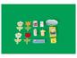 Jouets en bois, incluant des fleurs, des boîtes de lait et de céréales, et une assiette, sur fond vert.