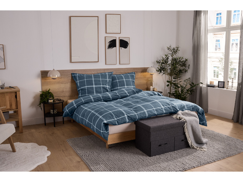 Chambre moderne avec lit, parure de lit à carreaux bleus et meubles en bois.