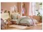 Chambre à coucher avec lit, dressing ouvert, plantes et décorations aux couleurs pastel.