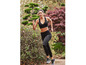 Une femme en soutien-gorge de sport et leggings noirs en train de courir dans un parc.