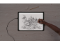 Main dessinant un croquis détaillé d'un moulin à eau sur une tablette lumineuse.