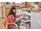 Femme organisant un meuble de cuisine avec tiroir coulissant pour épices et ustensiles.