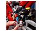 Une personne assemble une moto LEGO Technic rouge, avec des engrenages visibles.