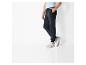 Un homme porte un pantalon de jogging bleu foncé et des baskets blanches.