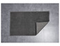 Un tapis de bain gris texturé sur un sol en carrelage gris.