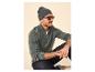 Homme en pull gris tricoté à demi-zip, jean foncé et bonnet gris, portant des lunettes de soleil.