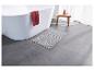 Un tapis de bain gris dans une salle de bain avec une baignoire blanche.