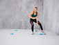 Une femme en tenue de sport fait un exercice avec des cônes.