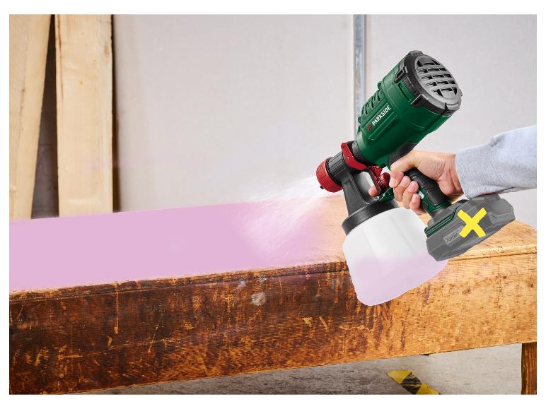Pistolet à peinture sans fil pulvérisant de la peinture rose sur une table en bois.