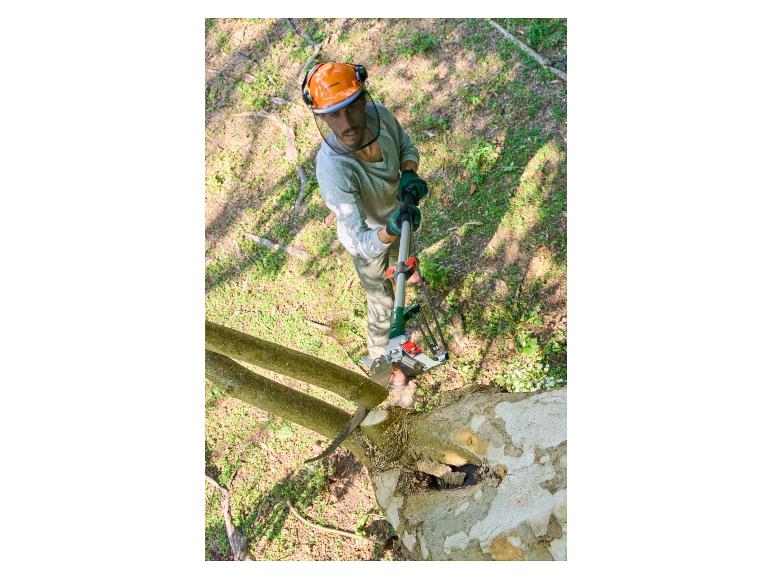 Un homme avec un casque coupe une branche d'arbre avec une scie à élaguer.