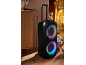 Grande enceinte portable avec lumières colorées et microfon dans une ambiance festive.