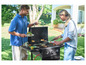 Un homme et une femme font griller des hamburgers sur un barbecue à gaz dans le jardin.