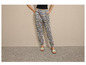 Femme portant un pantalon bleu à fleurs et des sandales blanches.