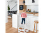 Un enfant debout sur un tabouret d'apprentissage blanc dans la cuisine.