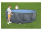 Deux personnes assemblent une piscine ronde dans le jardin.