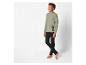 Un garçon porte un t-shirt vert à manches longues avec l'inscription 'Energy Level' et un pantalon noir.