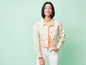 Une femme porte une veste en jean blanche, un t-shirt rose et un jean blanc.