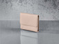 Un portefeuille en cuir rose sur un fond gris.