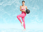 Une femme en leggings roses et un soutien-gorge de sport tient un ballon de médecine.