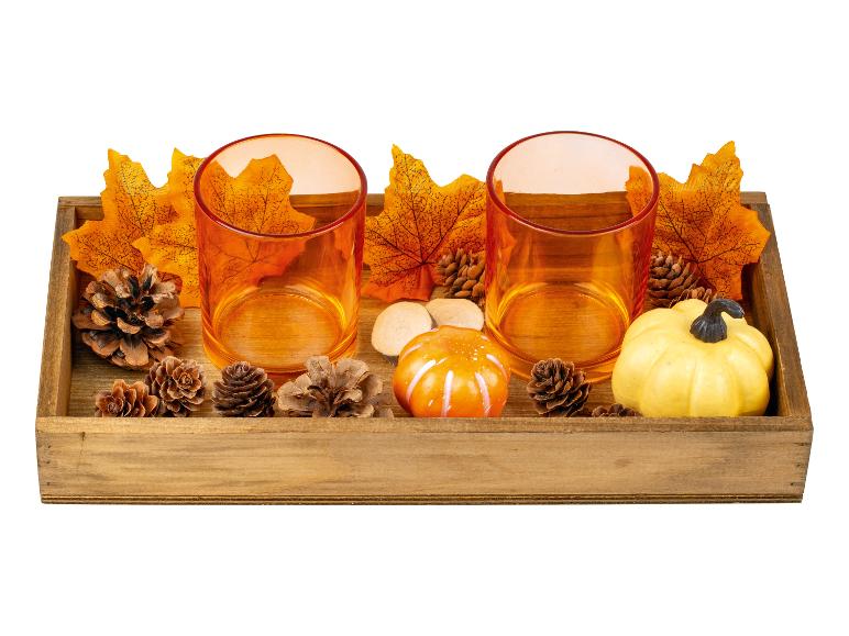 Plateau en bois avec bougeoirs orange, décorations d'automne et petites citrouilles.