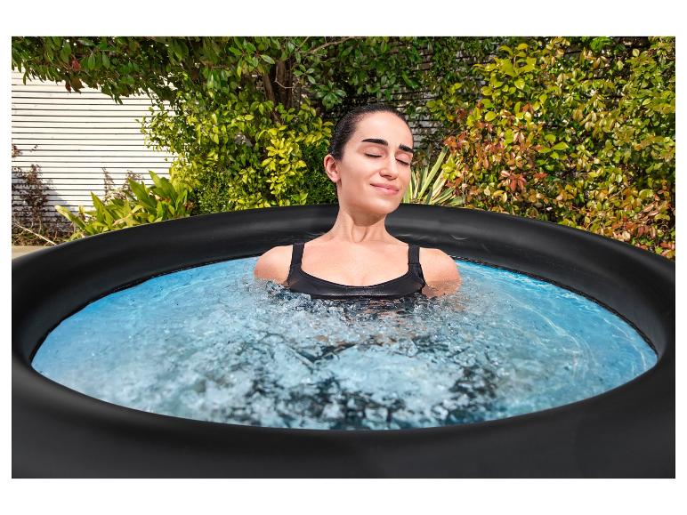 Femme se détend dans un jacuzzi extérieur, entourée de verdure.