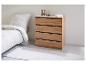 Une commode en bois avec quatre tiroirs, à côté d'un lit dans une chambre.