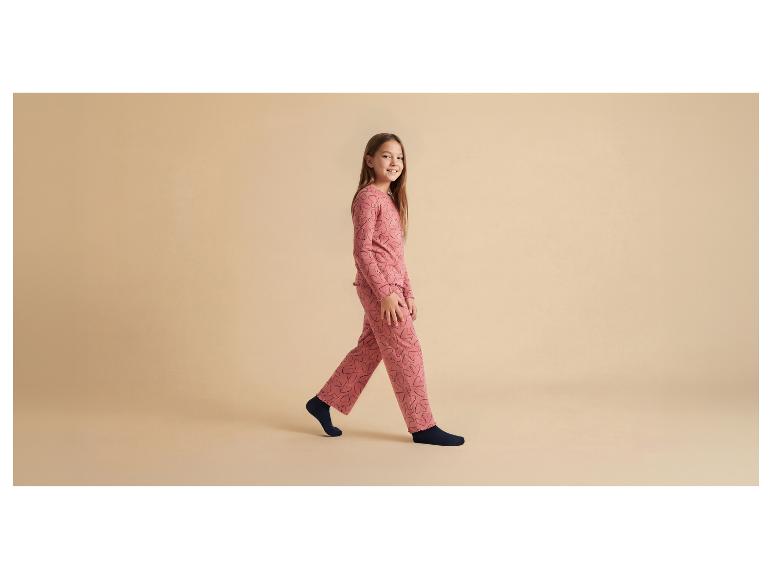 Fille en pyjama rose à cœurs noirs et chaussettes bleu foncé.