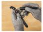 Un horloger portant des gants gris nettoie une montre avec une petite polisseuse.